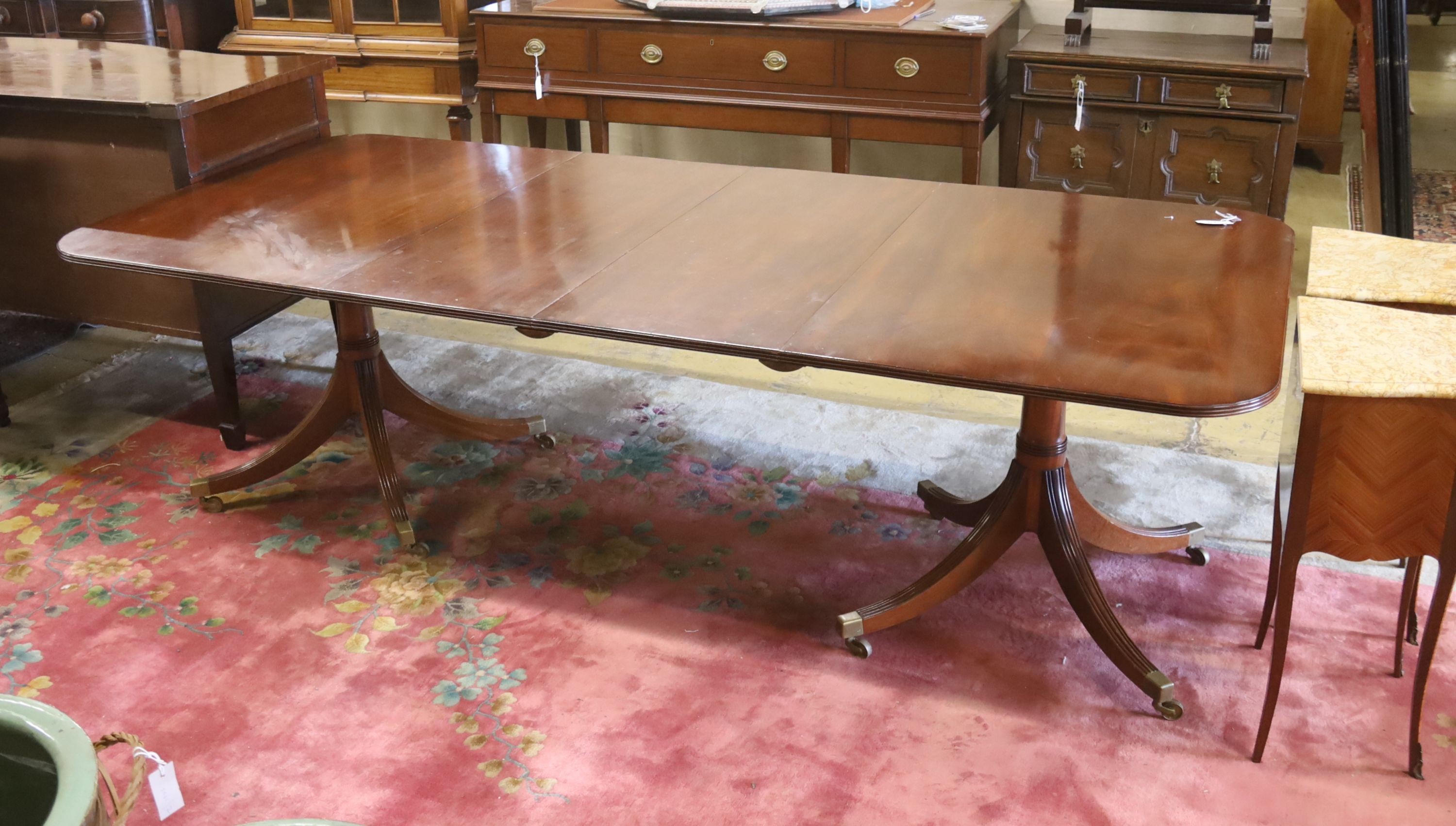 A reproduction George III style mahogany twin pillar extending dining table, two spare leaves, length 244cm extended, width 107cm, height 72cm